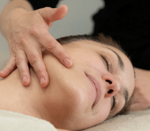 Une main masse délicatement le visage d’une cliente dans l'institut BL.